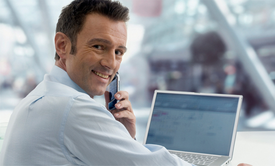 Die speziellen IT-Versicherungen von KuV24 IT-Experte vor dem Laptop mit Handy am Ohr